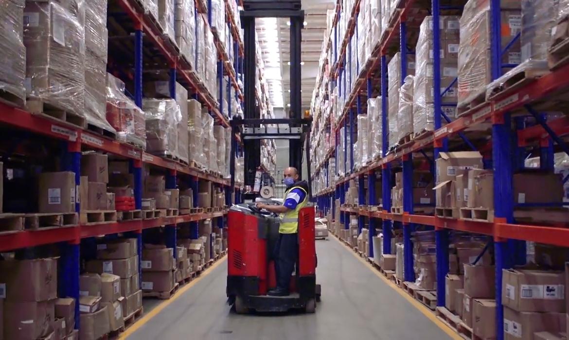 FESA pharmaceutical warehouse with worker operating equipment between high shelving racks of medical supplies